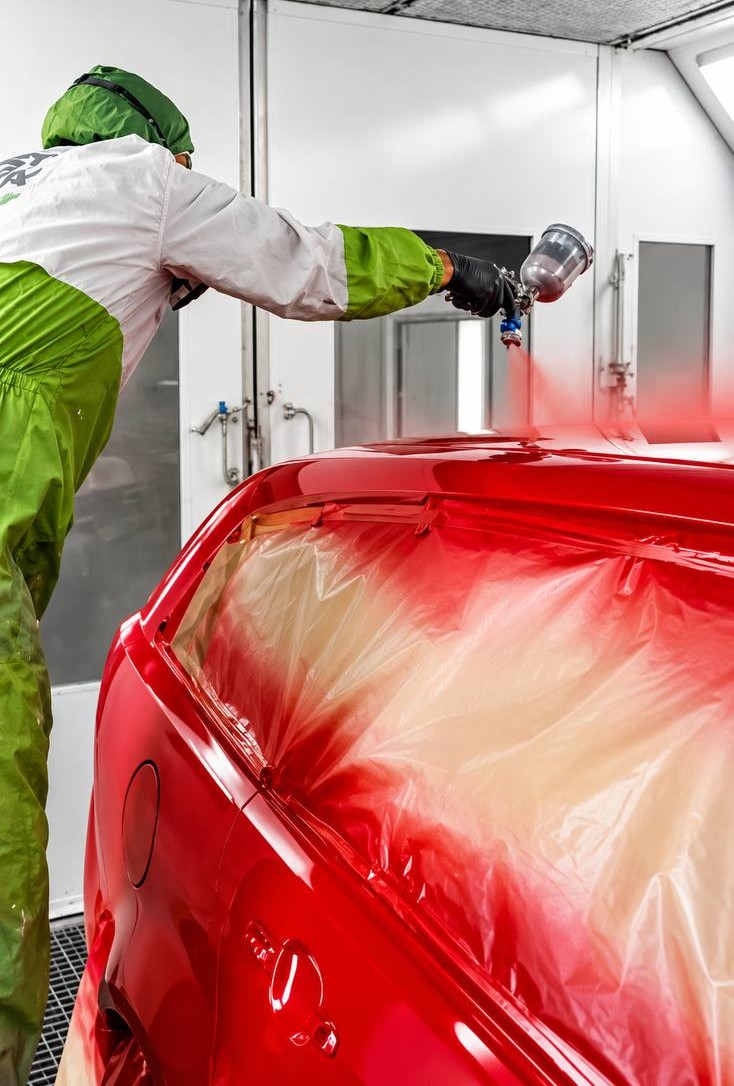 Spray painting a red car at Picassos Auto Body Repairs in South Nowra
